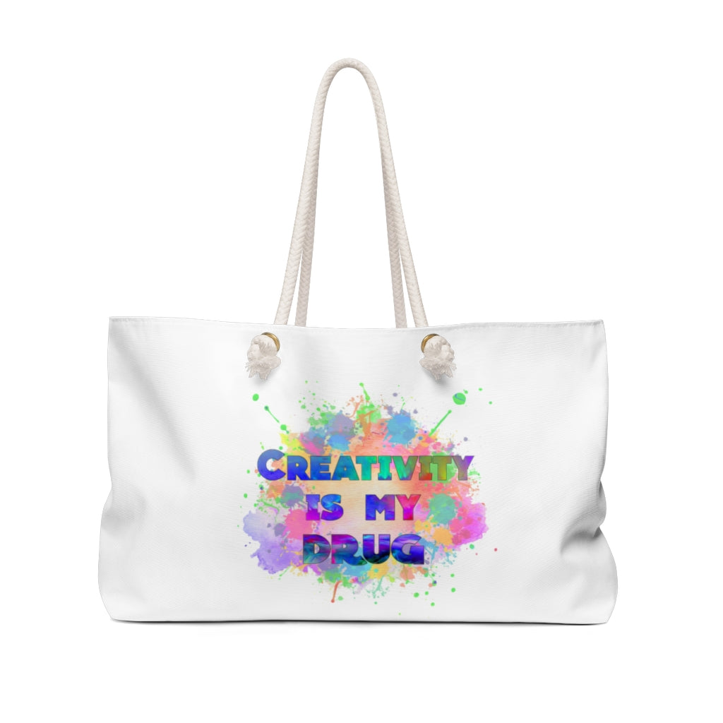 White oversized weekender bag with colorful "Creativity is my drug" text and rope handles