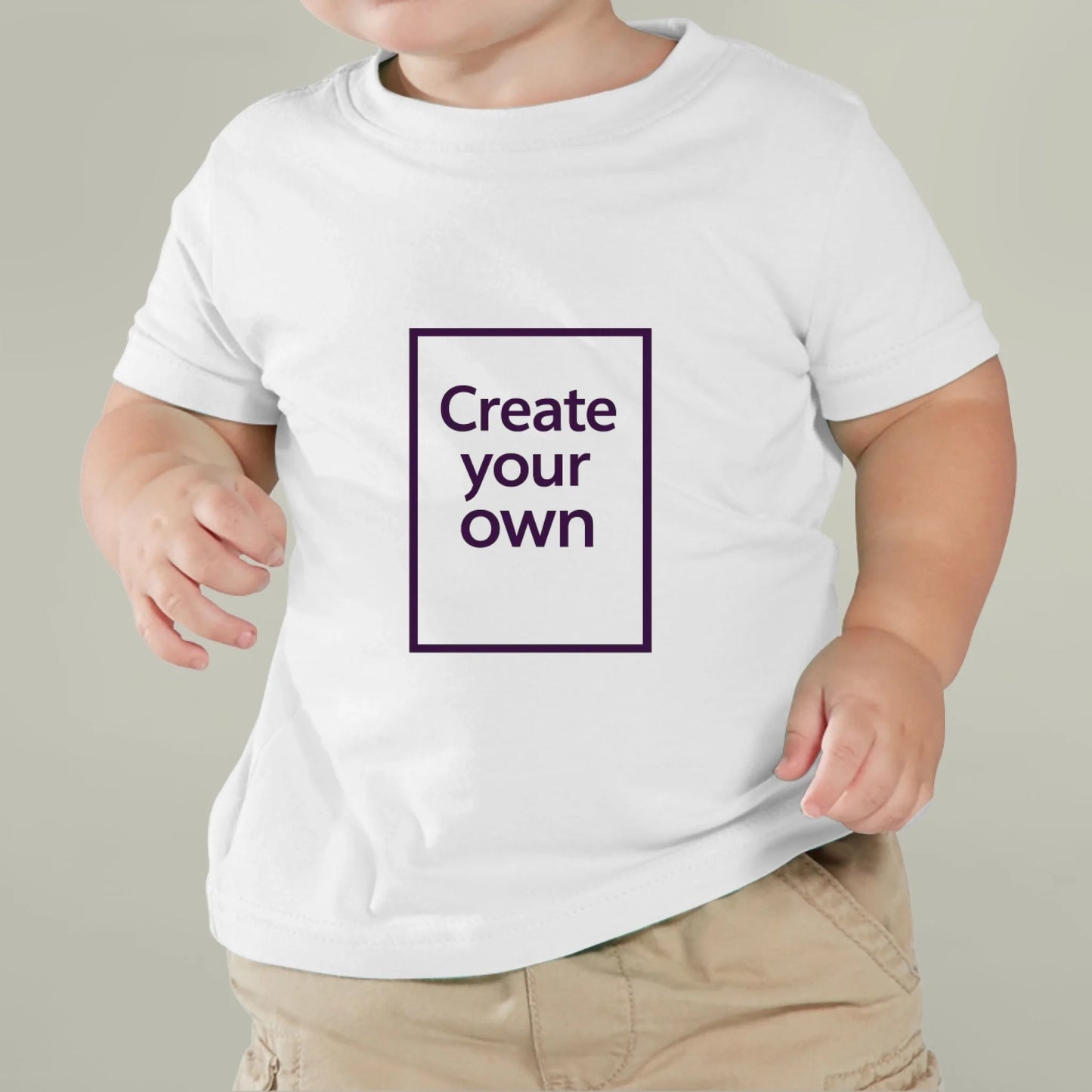 Child wearing a white t-shirt with 'Create your own' text on a plain background