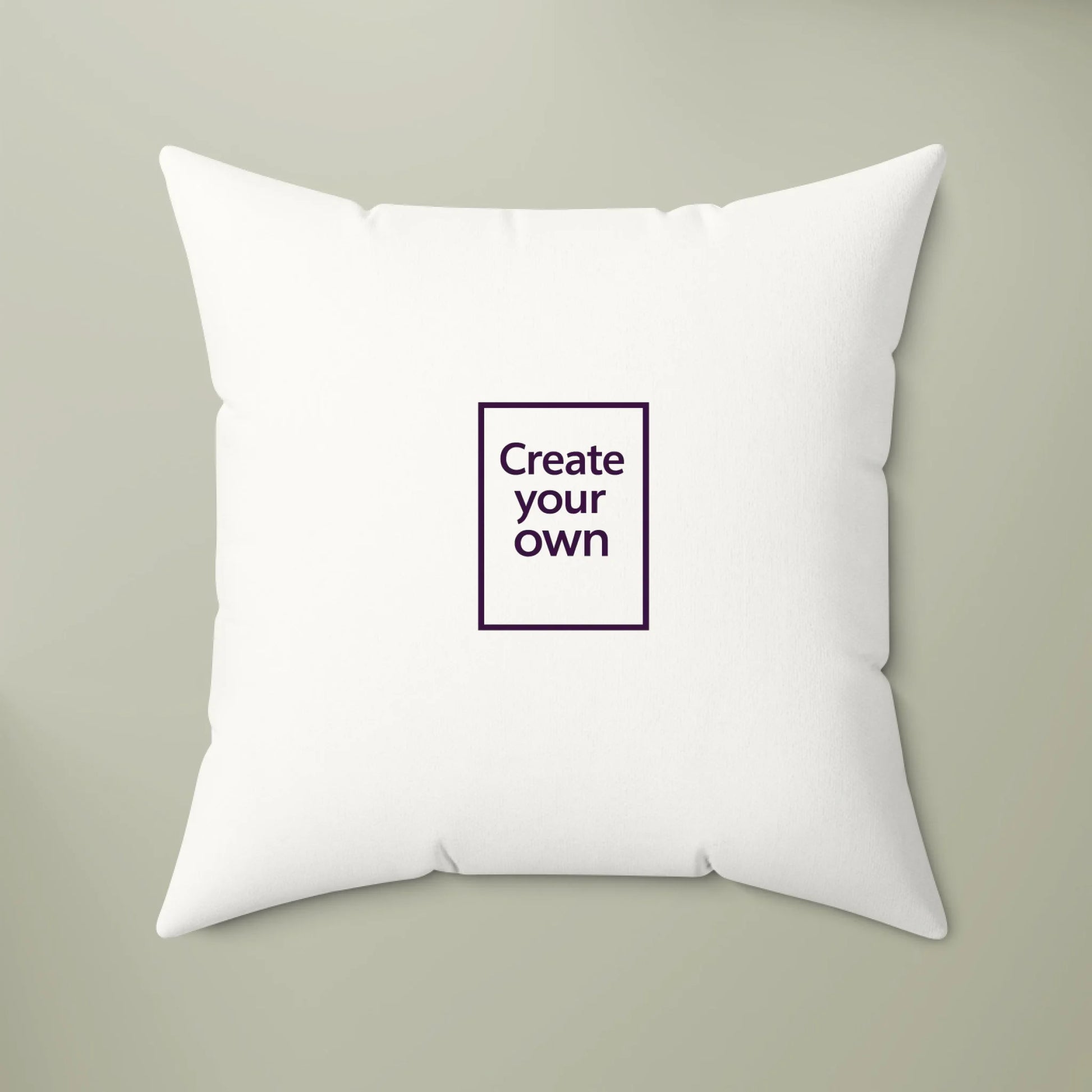 White pillow with a small square panel in the center that says 'Create your own' on a beige background